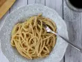 Porcja kremowego spaghetti cacio e pepe z widelcem, gotowa do zjedzenia.
