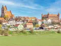 Zamek w Gniewie - ciekawostki. Imponująca twierdza i urokliwe miasteczko na tle błękitnego nieba.