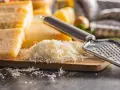 Stos tartego parmezanu, znanego jako parmigiano reggiano, obok bloków sera i tarki.