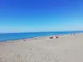 Słoneczny dzień na plaży w Marina di Bibbona. Ludzie odpoczywają na piasku, a morze lśni w słońcu.