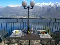 Stół z winem i jedzeniem na tarasie z widokiem na jezioro i ośnieżone góry. Idealne miejsce na romantyczną kolację z widokiem, prawdziwa "terrazza del brivido".