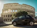 Czarny Fiat 500 pod Koloseum w Rzymie. Zastanawiasz się, ile się jedzie z Polski do Włoch samochodem?