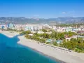 Widok z lotu ptaka na kurort nad morzem w Turcji z plażą, hotelami i górami w tle.