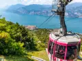 Różowa kolejka linowa Monte Baldo zjeżdża w dół, oferując widok na jezioro Garda i malownicze miasteczko.