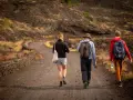 Trzy osoby wędrują po wulkanicznym krajobrazie Sycylii. Styczeń na wyspie oferuje przyjemną temperaturę do trekkingu.
