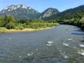 Rzeka Dunajec z tratwami i górami w tle.