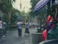 Procesja w deszczu na Bali, ludzie z parasolami i bambusowymi tyczkami.