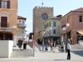 Rynek w Mestre z wieżą zegarową i ludźmi spacerującymi po placu.