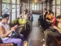 Wnętrze tramwaju w Mediolanie. Pasażerowie korzystają z mediolańskiej komunikacji miejskiej, przeglądając telefony.
