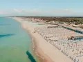 Widok z lotu ptaka na plażę w Marina di Cecina, Toskania, z rzędami leżaków i parasoli.