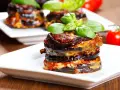 Pyszna parmigiana di melanzane, warstwy bakłażana z sosem pomidorowym i serem, udekorowana bazylią.