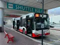 Autobus wahadłowy z lotniska do centrum miasta, z otwartymi drzwiami, gotowy do odjazdu.