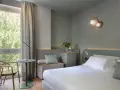 Nowoczesny pokój hotelowy z łóżkiem, fotelem i oknem z widokiem na zieleń.