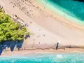 Chorwacja plaże piaszczyste, z turkusową wodą i zielonymi drzewami. Leżaki i parasole czekają na plażowiczów.
