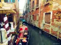 Gondola z czerwonymi poduszkami i dywanem w wąskim kanale Wenecji, otoczonym starymi ceglanymi budynkami.