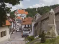 Widok na urokliwą, brukowaną uliczkę Kazimierza Dolnego z zabytkową architekturą i kościołem w tle.
