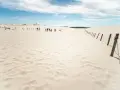 Spacerem po ruchomych wydmach w Słowińskim Parku Narodowym. Piasek i błękitne niebo tworzą pustynny krajobraz.
