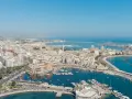 Widok na port w Bari, gdzie cumują jachty i statki. W tle widać miasto i morze, a ruch uliczny świadczy o sprawnym transporcie.