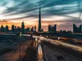 Wieczorny widok na Dubaj z Burj Khalifa, gdzie światła samochodów tworzą smugi na autostradzie. Ciekawostki o tym drapaczu chmur mogą dotyczyć jego wysokości i budowy.