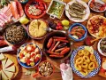 Tapas co to? Obficie zastawiony stół pełen hiszpańskich przekąsek: kiełbaski, krewetki, kalmary, owoce morza, sery, wędliny i tortilla.