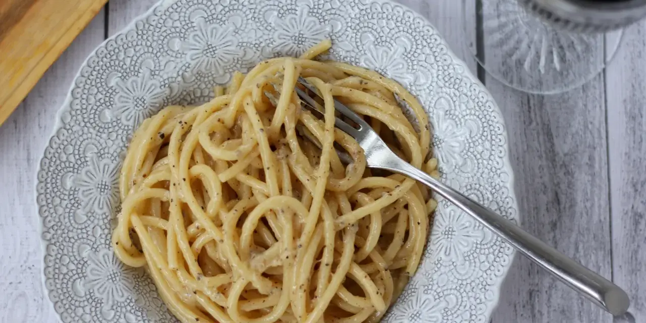 Porcja kremowego spaghetti cacio e pepe z widelcem, gotowa do zjedzenia.