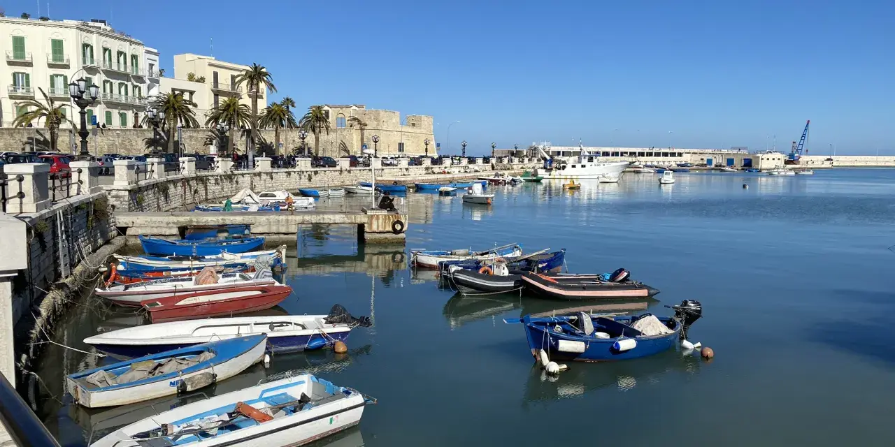 Widok na port w Bari z łodziami i budynkami w tle.