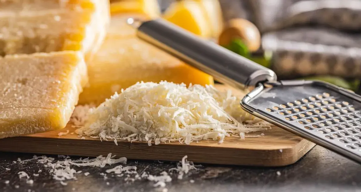 Stos tartego parmezanu, znanego jako parmigiano reggiano, obok bloków sera i tarki.