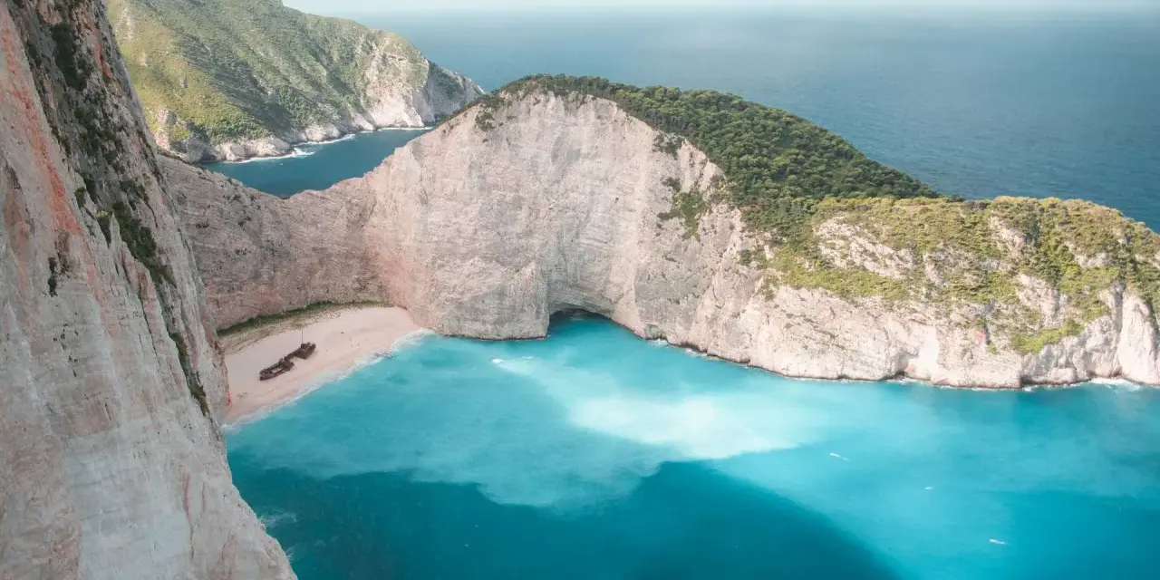 Zatoka Wraku na Zakynthos z turkusową wodą i klifami.