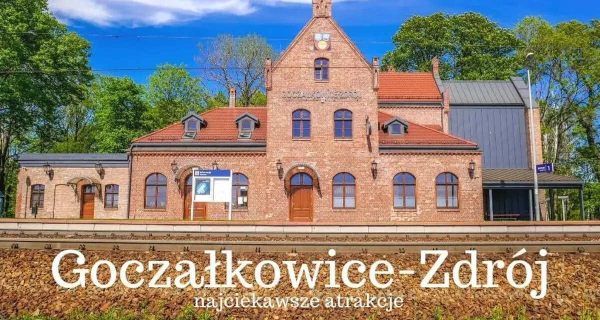 Ceglana stacja kolejowa Goczałkowice-Zdrój z czerwonym dachem i zielonymi drzewami w tle.