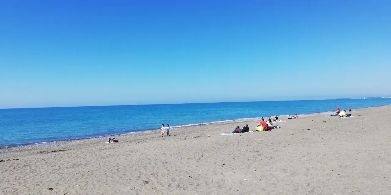 Słoneczny dzień na plaży w Marina di Bibbona. Ludzie odpoczywają na piasku, a morze lśni w słońcu.