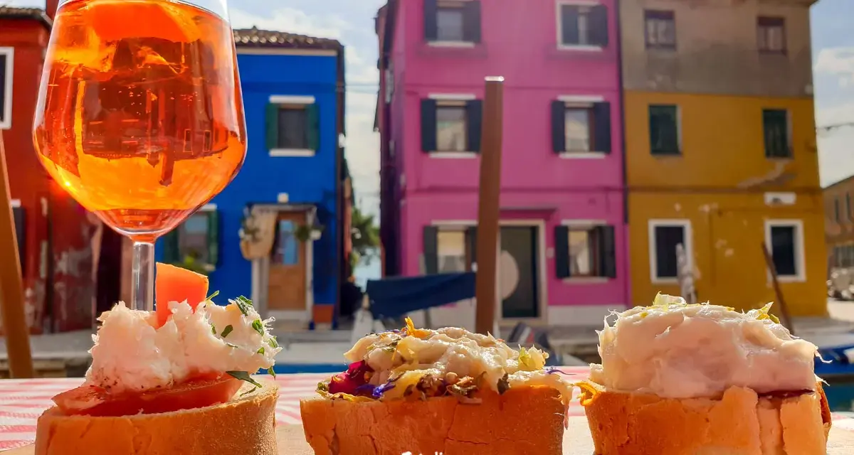 Co zjeść w Wenecji? Aperol i bruschetty na tle kolorowych domów Burano. Idealne połączenie smaków i widoków.