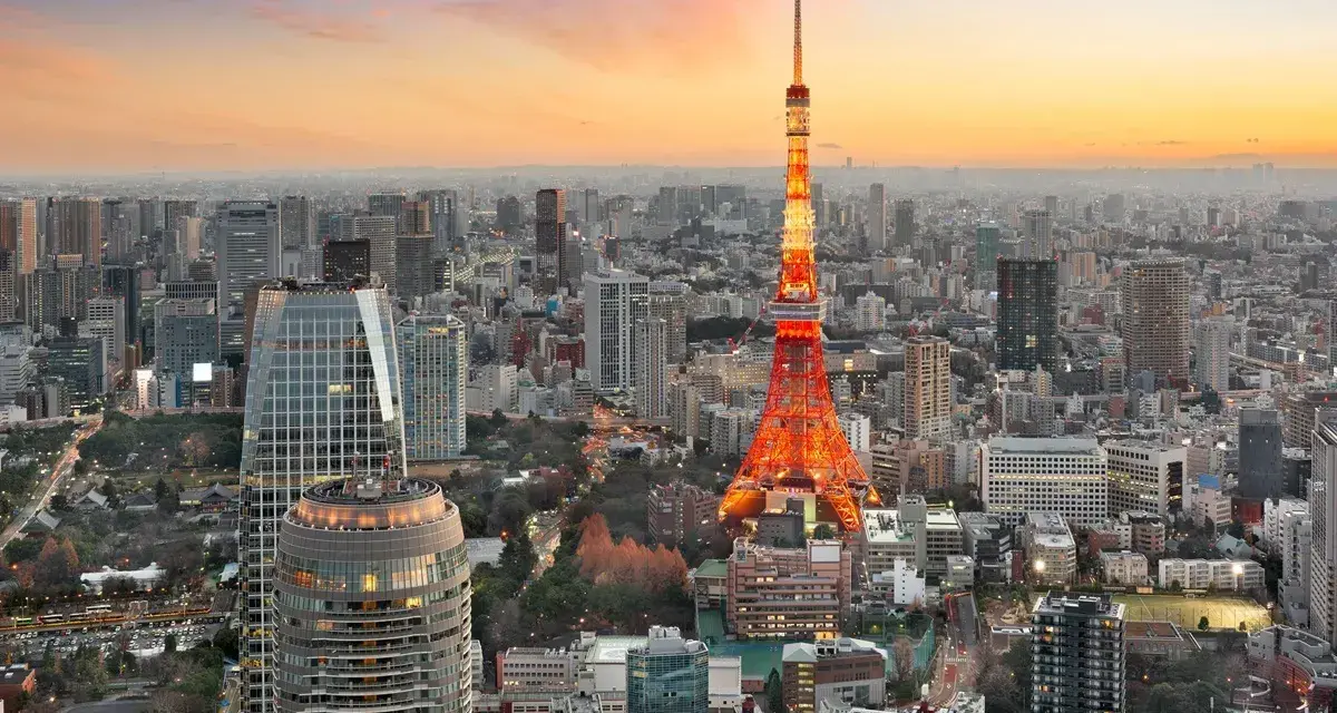 Widok na Tokio, jedno z 10 największych miast na świecie, z wieżą Tokyo Tower w pomarańczowych barwach o zachodzie słońca.