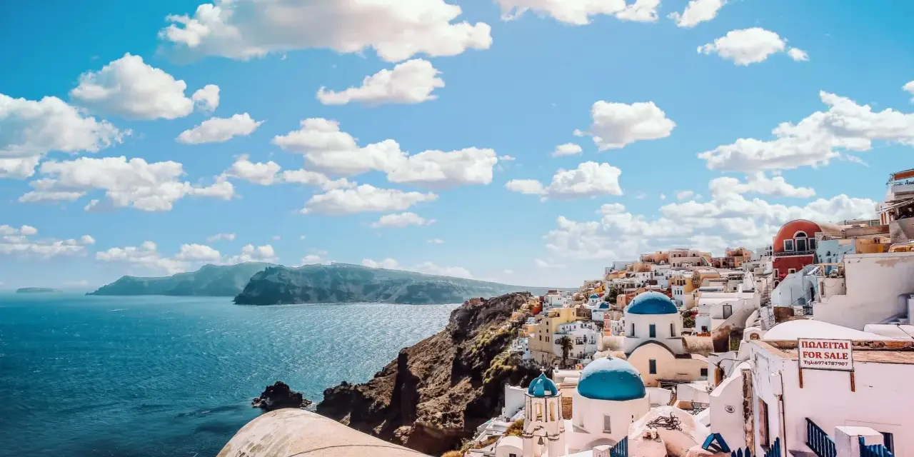 Santorini, Grecja. W jakim języku mówi się w Grecji? Po grecku! Białe domy, niebieskie kopuły i morze.