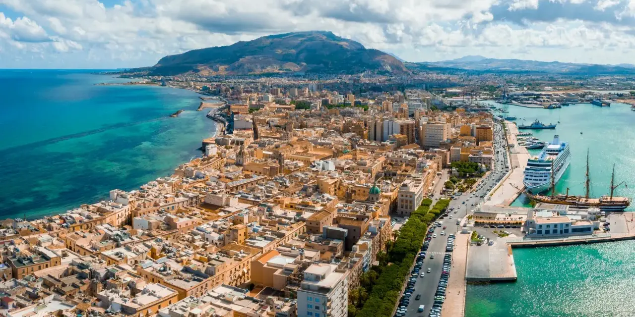 Widok na Trapani, Sycylia. Miasto z widokiem na turkusowe morze i góry. Zobacz, co warto zobaczyć w Trapani: port z luksusowym rejsem i zabytkowymi żaglowcami.