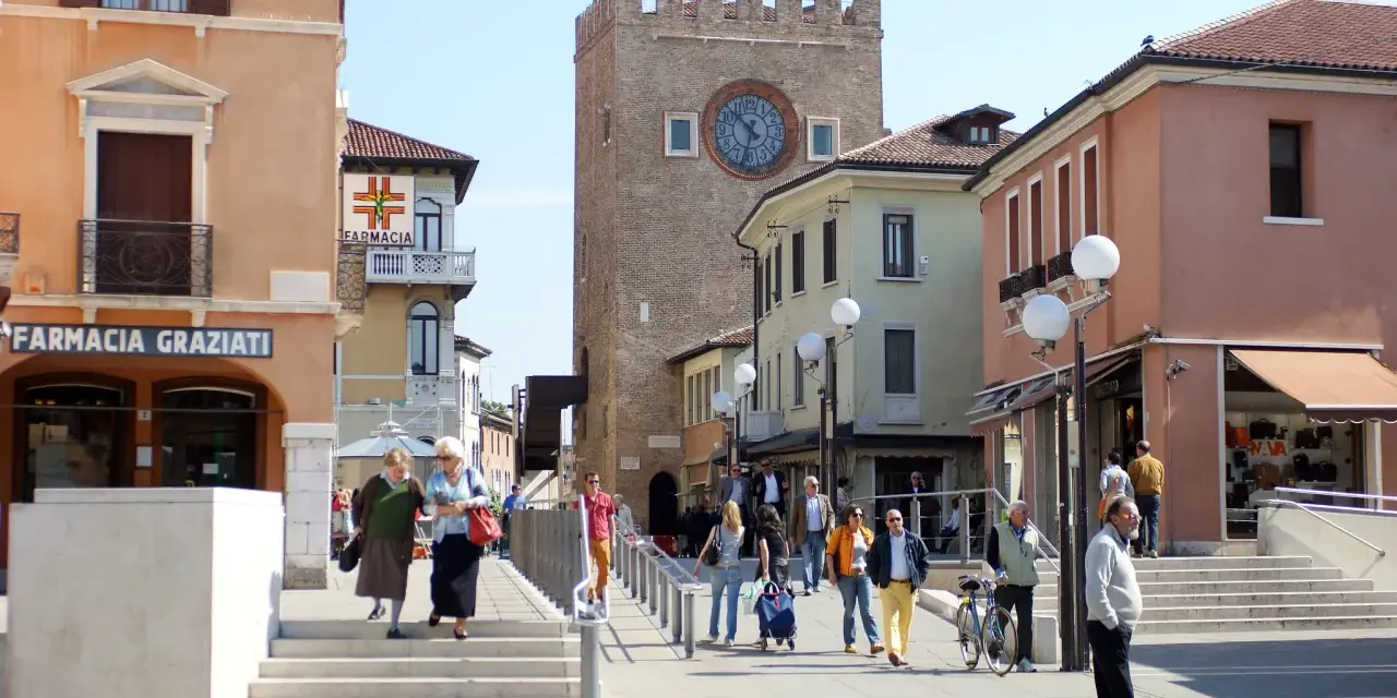 Rynek w Mestre z wieżą zegarową i ludźmi spacerującymi po placu.