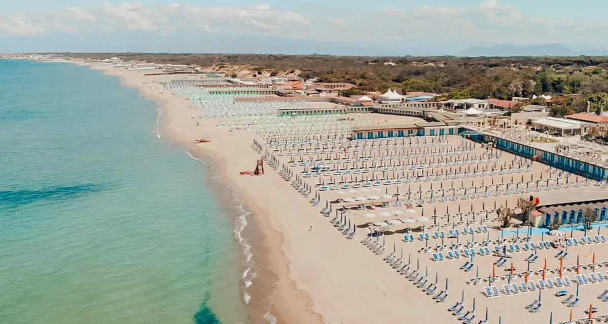 Widok z lotu ptaka na plażę w Marina di Cecina, Toskania, z rzędami leżaków i parasoli.