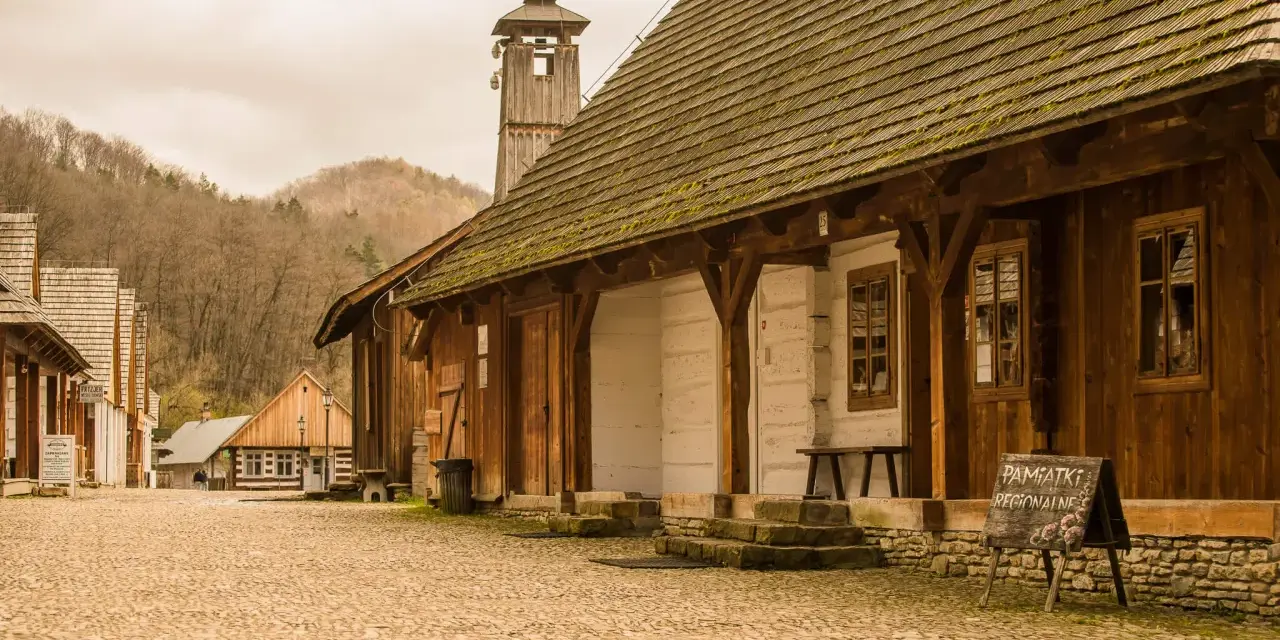 Drewniana zabudowa skansenu, wieża z wiatrowskazem i tablica "Pamiątki Regionalne" - tak z czego słynie Sanok.