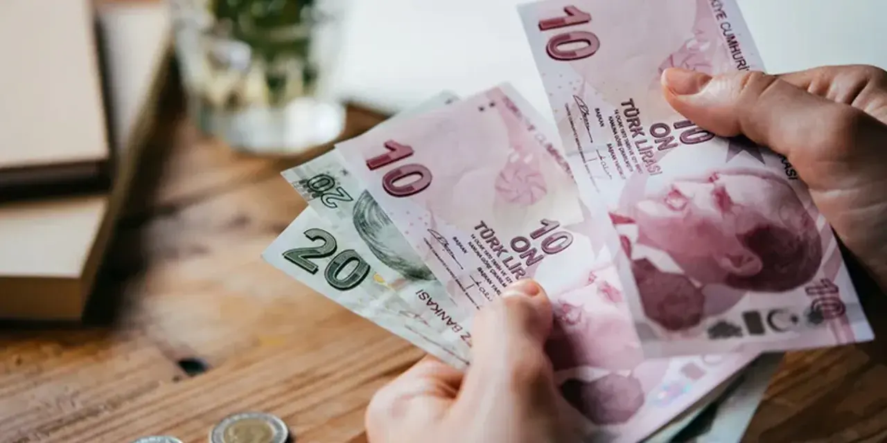 Ręka trzyma banknoty 10 i 20 lir tureckich. To pokazuje, czym płacić w Turcji.