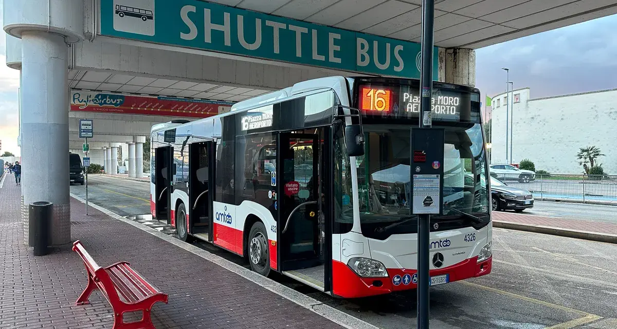 Autobus wahadłowy z lotniska do centrum miasta, z otwartymi drzwiami, gotowy do odjazdu.