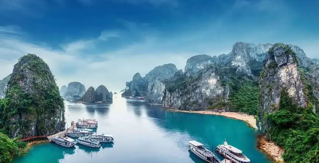 Zatoka Ha Long we Wietnamie z łodziami i skalistymi wyspami.
