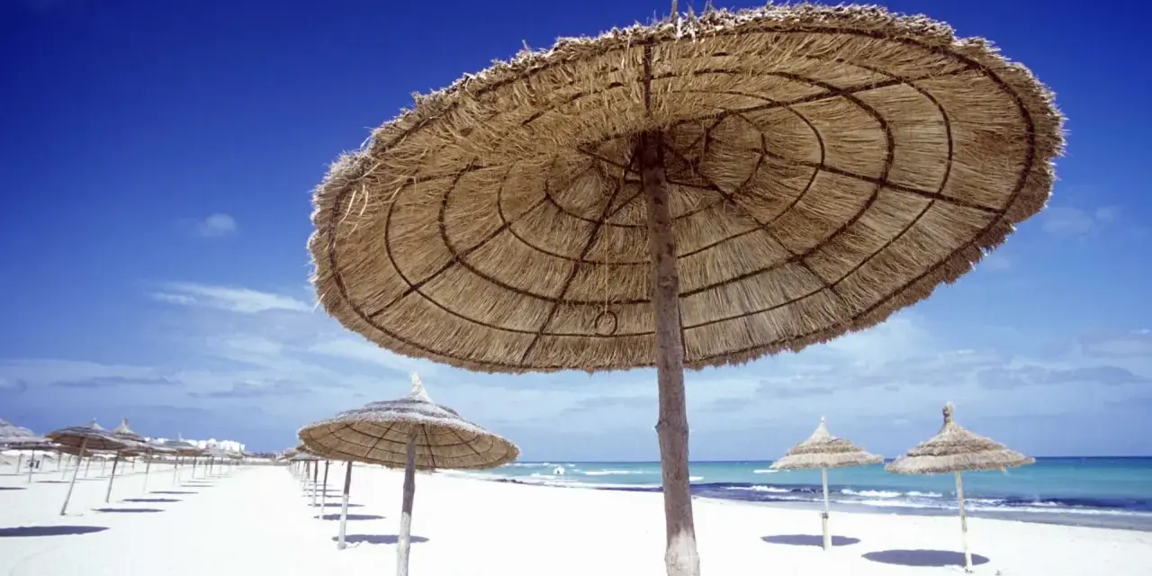 Słomiane parasole na pustej plaży w Tunezji. Marzec zapowiada piękną pogodę i spokojne morze.