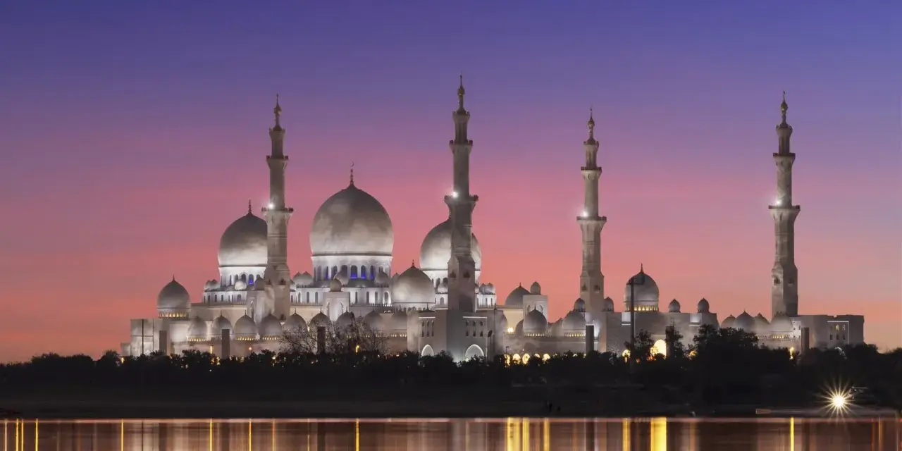 Wspaniały meczet oświetlony nocą, odbijający się w wodzie. Idealny widok, kiedy jest Ramadan.