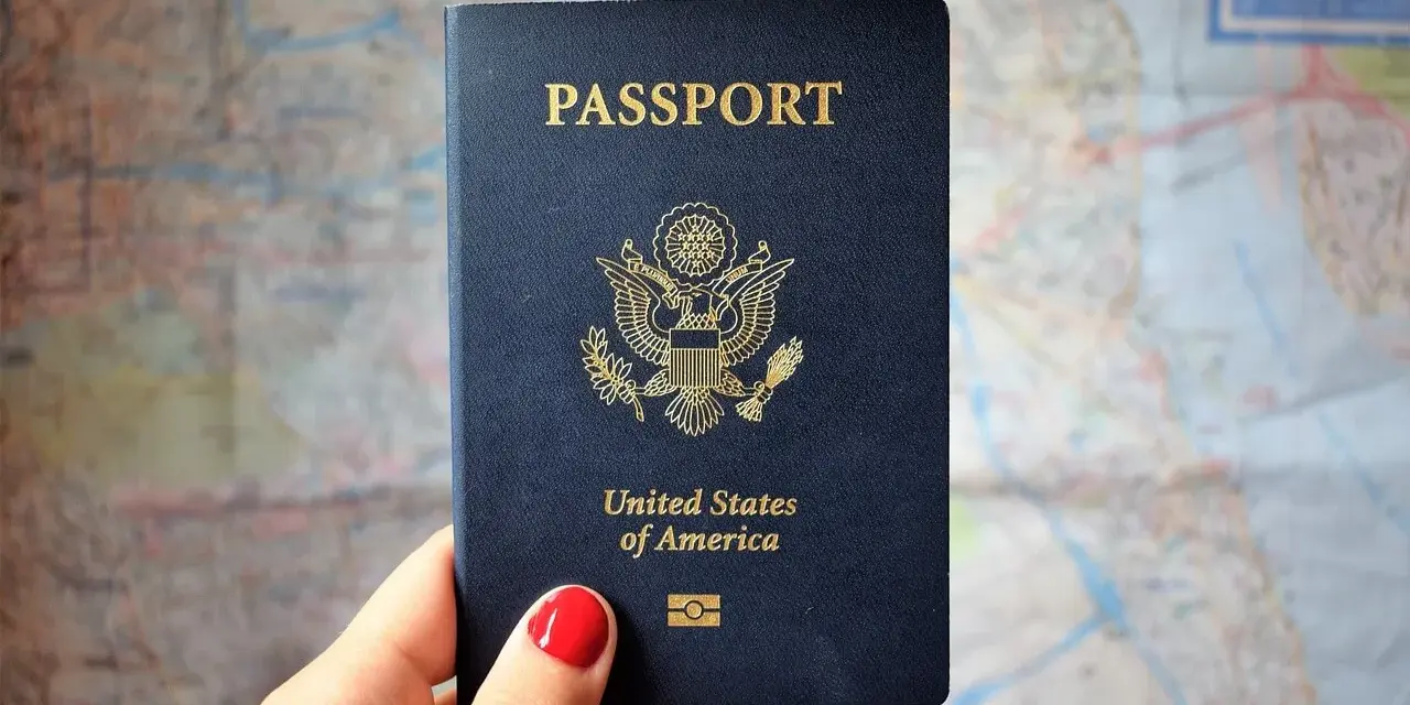 Dłoń trzyma paszport USA na tle mapy. Czas oczekiwania na paszport może być długi, ale podróż warta jest tej chwili.