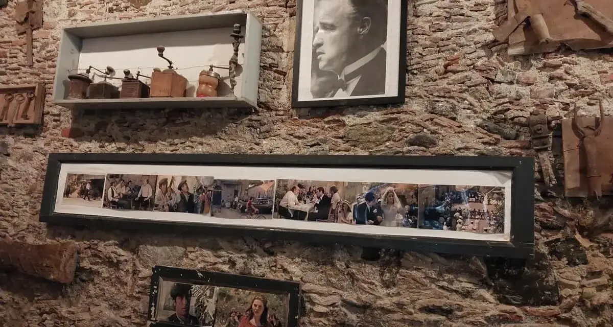 Pamiątki z miejsc, gdzie kręcono Ojca Chrzestnego: portret Marlona Brando, kolaż scen z filmu i stare młynki do kawy.