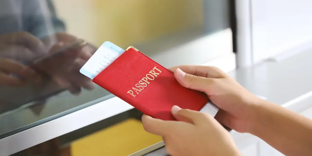 Ręce trzymają czerwony paszport z biletem lotniczym. Pamiętaj, czego nie wolno wywozić z Sycylii, by uniknąć problemów.