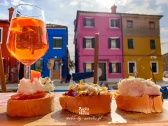 Co zjeść w Wenecji? Aperol i bruschetty na tle kolorowych domów Burano. Idealne połączenie smaków i widoków.
