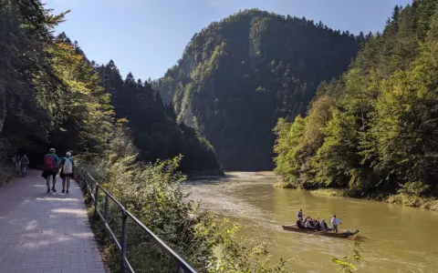 Ścieżka pieszo-rowerowa nad Dunajcem, w tle góry i tratwa.