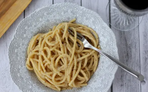 Porcja kremowego spaghetti cacio e pepe z widelcem, gotowa do zjedzenia.