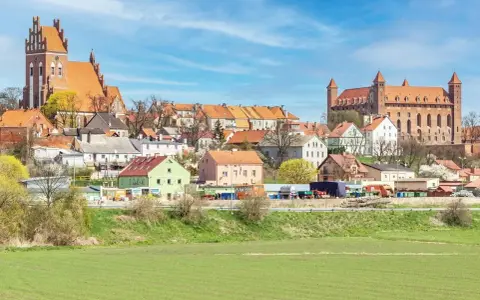 Zamek w Gniewie - ciekawostki. Imponująca twierdza i urokliwe miasteczko na tle błękitnego nieba.