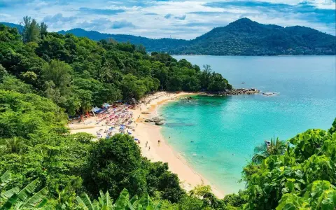 Tropikalna plaża z turkusową wodą, zielonymi wzgórzami i leżakami.